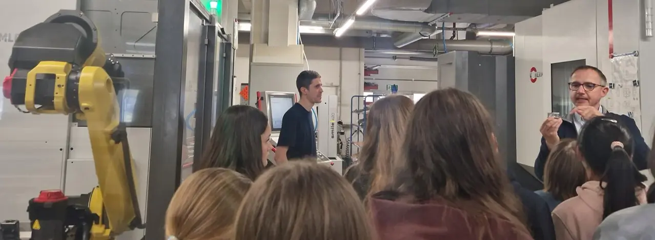 Figure 7: Thomas Müller explains to the girls how CNC machines mill the housing for a pump head from a block of metal and why precision is crucial in this process. On the left is one of the robotic arms that continues working even at night, allowing employees to focus solely on daytime work and more demanding tasks.