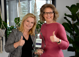 HR Officer and CEO presenting glass trophy, smiling with thumbs up