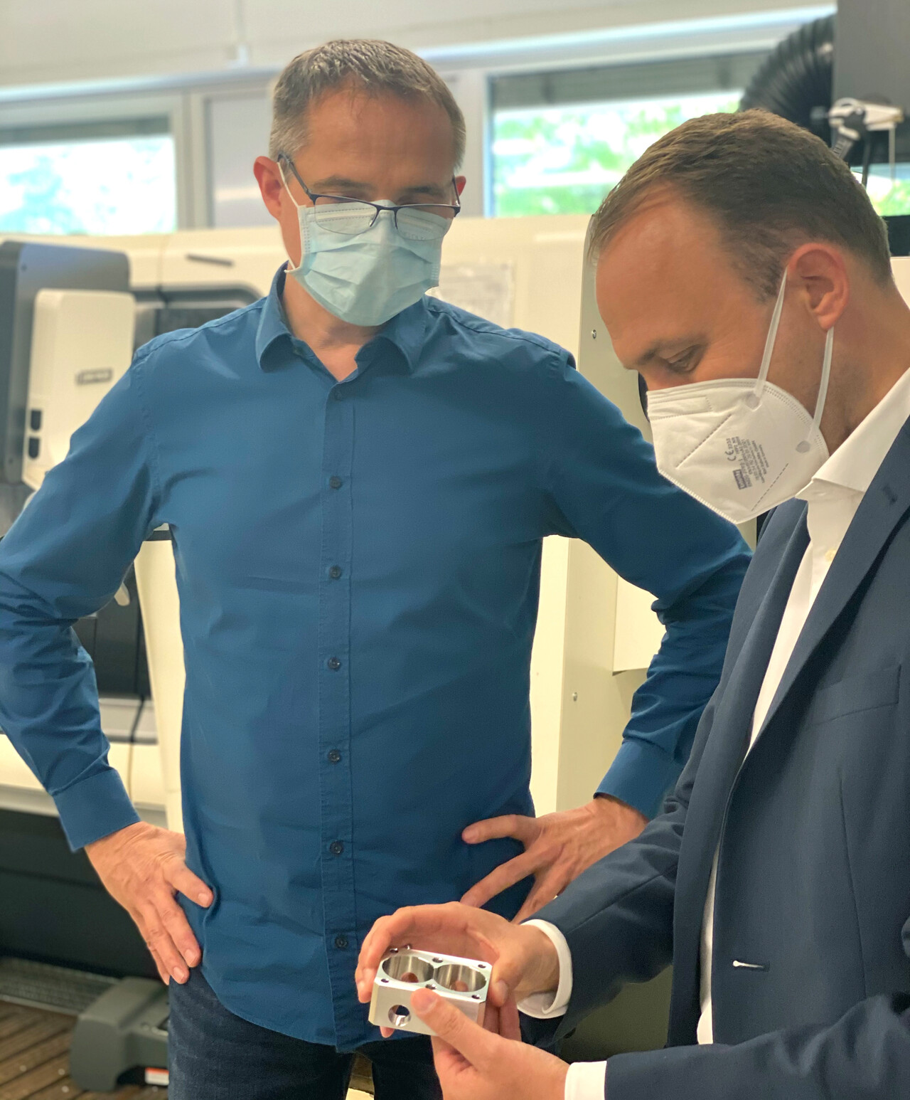 Department head Thomas Müller shows Sebastian Czaja a freshly CNC-machined important component for the high-pressure pumps.