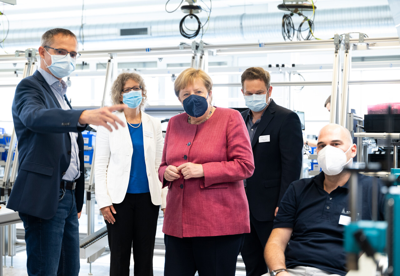 Production head Müller explains a work area in module production to Dr. Merkel