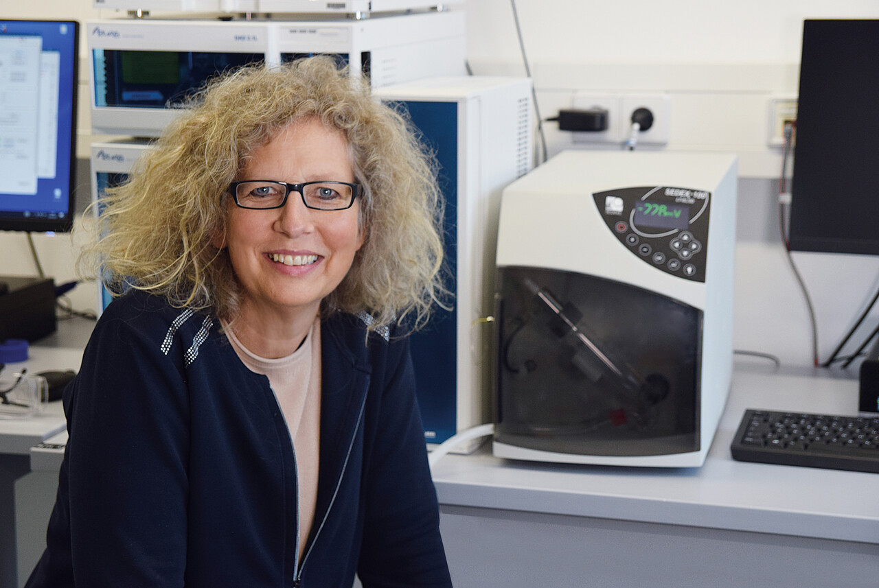 Managing Director Alexandra Knauer sitting in front of a KNAUER AZURA HPLC system with a SEDEX-100 detector