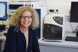 Geschäftsführerin Alexandra Knauer sitzt vor KNAUER AZURA HPLC-System mit SEDEX-100 Detektor